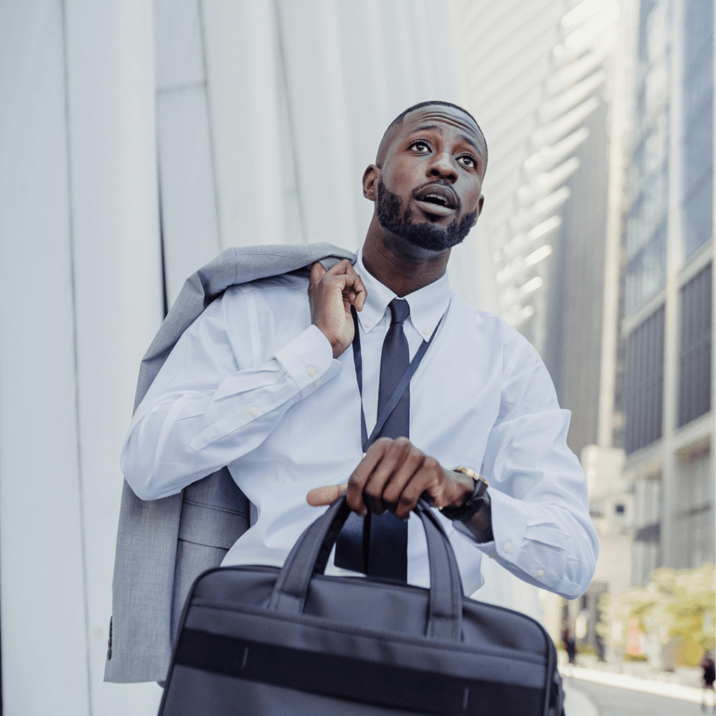 A man dressed in a white shirt and tie carries a briefcase, suggesting a professional setting.